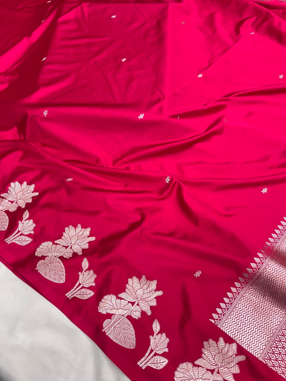 A model gracefully presenting a luxurious hot pink Banarasi Mashru silk saree adorned with intricate silver zari floral motifs and a detailed geometric border.