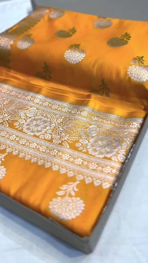 Radiant golden yellow Banarasi Mashru soft silk saree featuring intricate silver and gold zari work, a heavy floral border, and classic woven buttis.