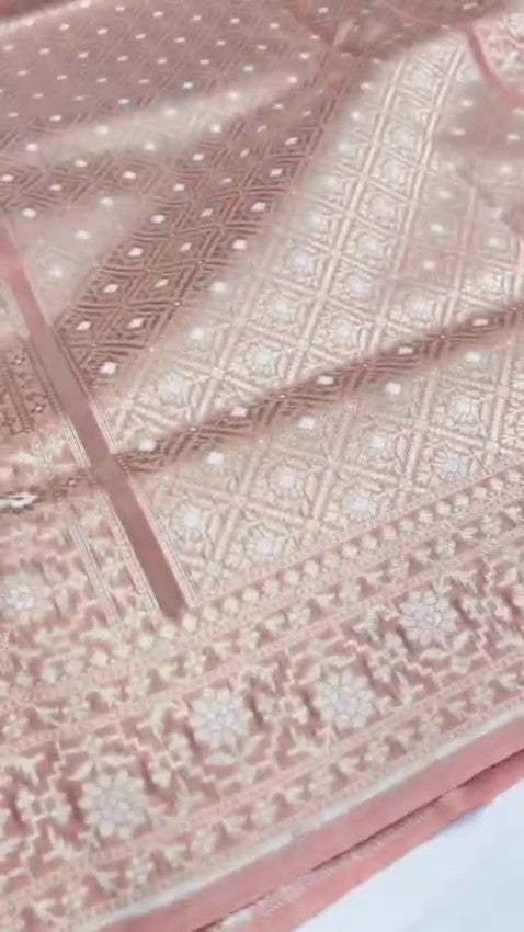 Pastel peach Banarasi mercerised cotton saree with intricate Sona Rupa silver and gold zari weaving, posed against a modern architectural background.