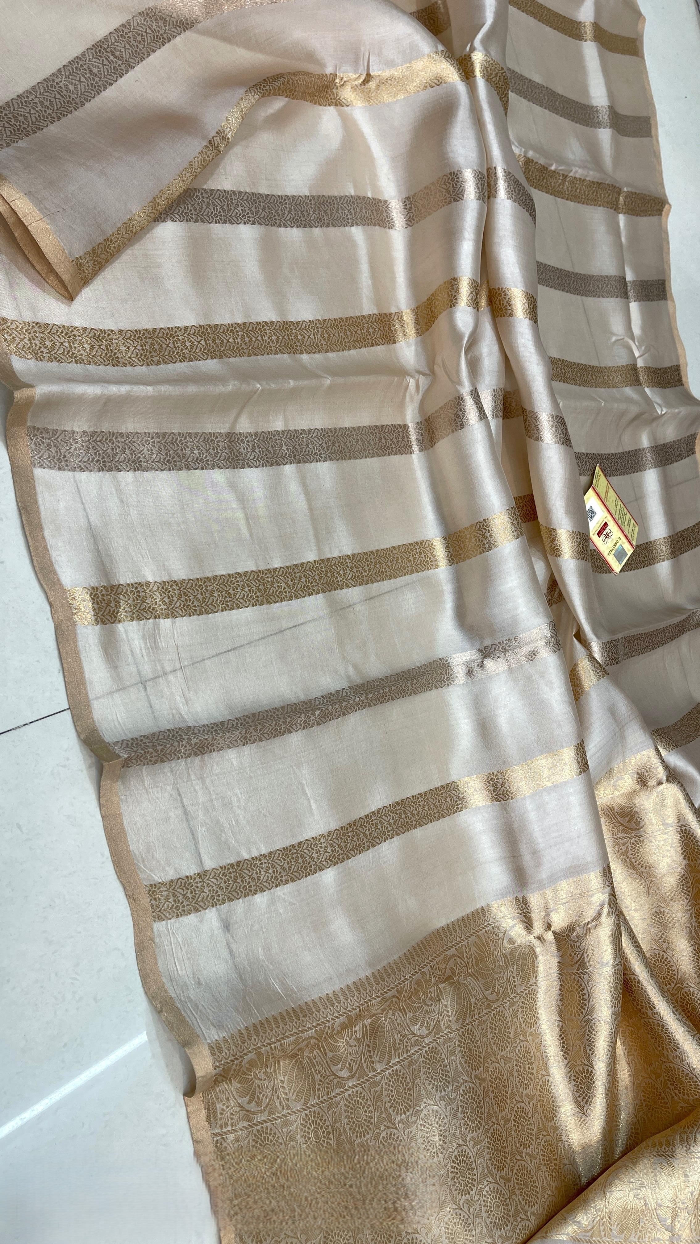 Ivory Banarasi Raw Mango Silk saree with horizontal Gold and Silver zari stripes, Kaduwa weaving, and a mustard yellow blouse.