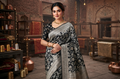 A model wearing Sona Rupa Jangla floral and vine pattern woven across the black katan silk saree.
