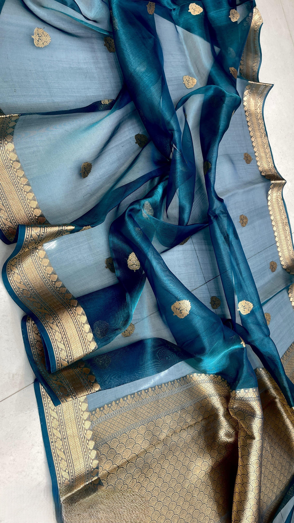 Peacock blue Banarasi handloom kora tissue silk saree featuring shimmering zari weaving, intricate borders, and a certified authentic finish.
