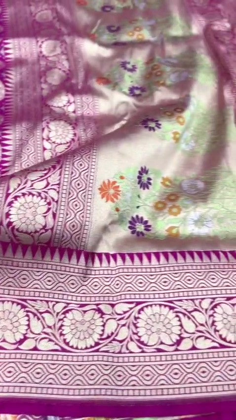 A stunning pink Banarasi handloom pure Katan silk saree adorned with multicolored Meenakari floral patterns and a rich silver zari border, perfect for weddings.