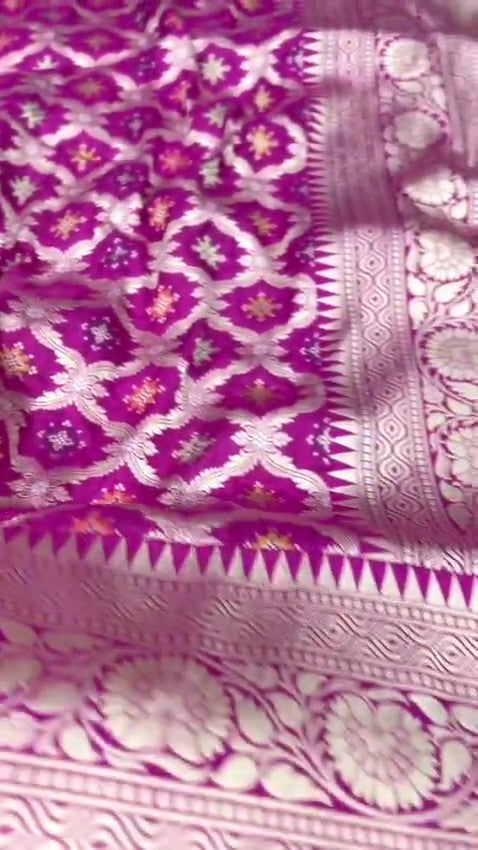 A stunning pink Banarasi handloom pure Katan silk saree adorned with multicolored Meenakari floral patterns and a rich silver zari border, perfect for weddings.