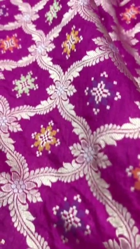 A stunning pink Banarasi handloom pure Katan silk saree adorned with multicolored Meenakari floral patterns and a rich silver zari border, perfect for weddings.