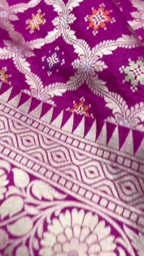 A stunning pink Banarasi handloom pure Katan silk saree adorned with multicolored Meenakari floral patterns and a rich silver zari border, perfect for weddings.