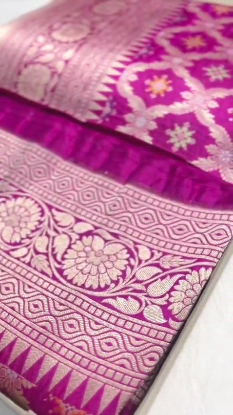 A stunning pink Banarasi handloom pure Katan silk saree adorned with multicolored Meenakari floral patterns and a rich silver zari border, perfect for weddings.