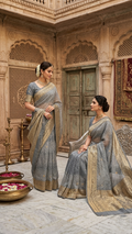 Two models in an ethnic Banarasi courtyard wearing charcoal grey Kora Tissue silk sarees featuring diagonal Arasi Shibori patterns and gold zari borders.