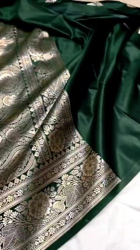 A stunning deep bottle green Banarasi Mashru soft silk saree, adorned with intricate, traditional floral and paisley patterns handwoven using shining copper zari throughout the border, pallu, and body.
