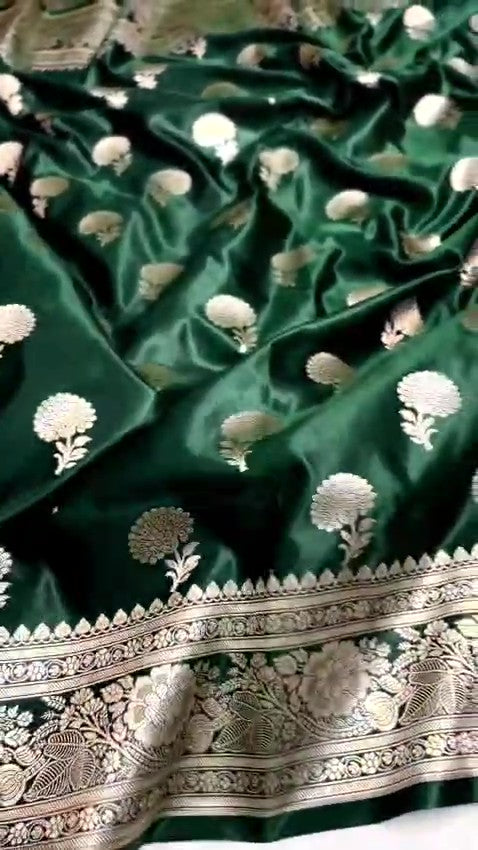 A stunning deep bottle green Banarasi Mashru soft silk saree, adorned with intricate, traditional floral and paisley patterns handwoven using shining copper zari throughout the border, pallu, and body.