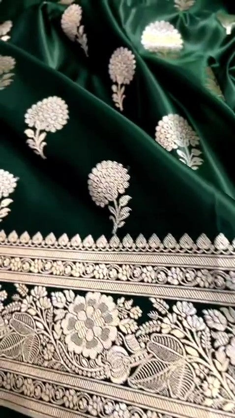 A stunning deep bottle green Banarasi Mashru soft silk saree, adorned with intricate, traditional floral and paisley patterns handwoven using shining copper zari throughout the border, pallu, and body.