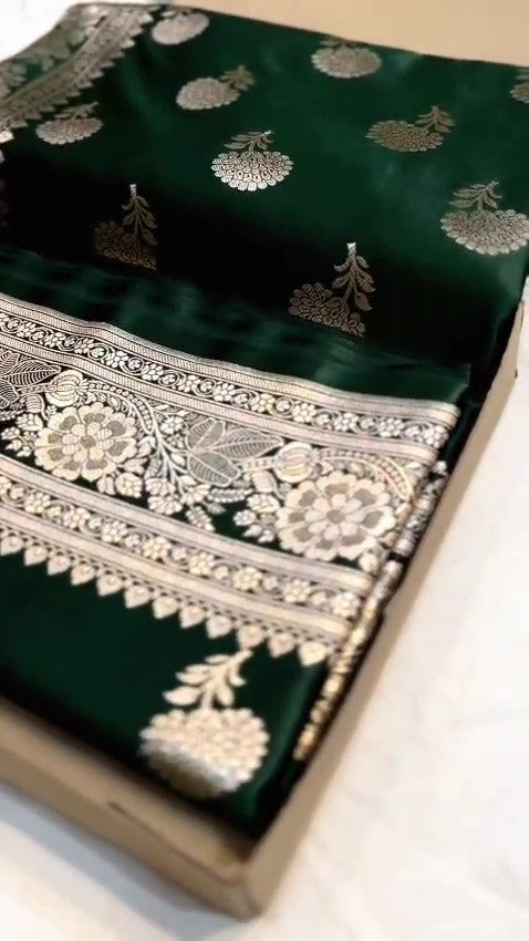 A stunning deep bottle green Banarasi Mashru soft silk saree, adorned with intricate, traditional floral and paisley patterns handwoven using shining copper zari throughout the border, pallu, and body.