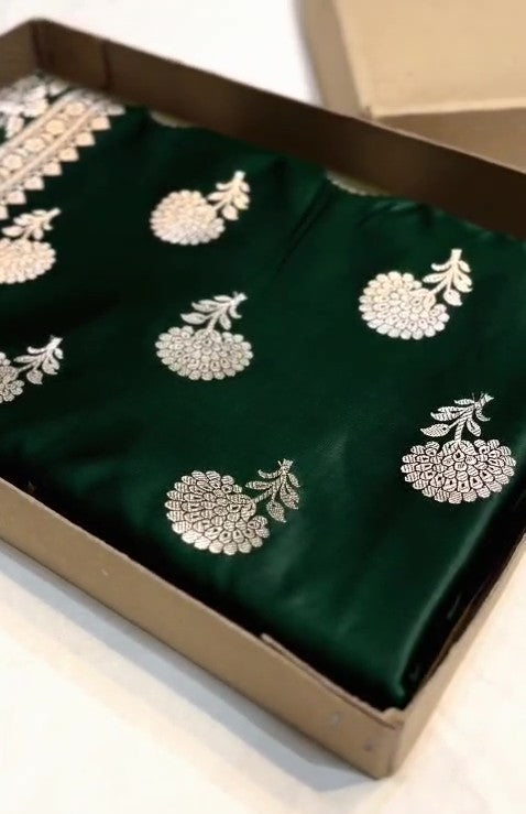 A stunning deep bottle green Banarasi Mashru soft silk saree, adorned with intricate, traditional floral and paisley patterns handwoven using shining copper zari throughout the border, pallu, and body.