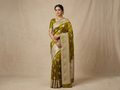 A model elegantly draped in a rich olive green Banarasi Mashru soft silk saree featuring intricate copper zari floral butas and an ornate traditional silver zari border.