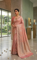A model showcasing a pastel peach Banarasi mercerised cotton saree with intricate Sona Rupa silver and gold zari weaving, posed against a modern architectural background.