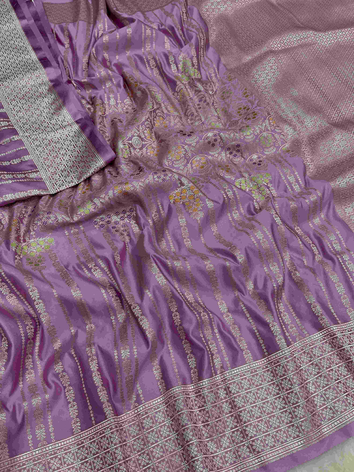 Folded lavender Banarasi mashru soft silk saree featuring intricate all-over floral jangla weave and subtle meenakari detailing.