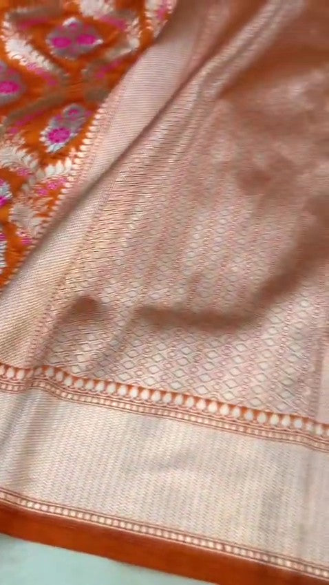 Orange Banarasi handloom pure chiniya silk saree featuring intricate silver sona roopa meenakari patterns.