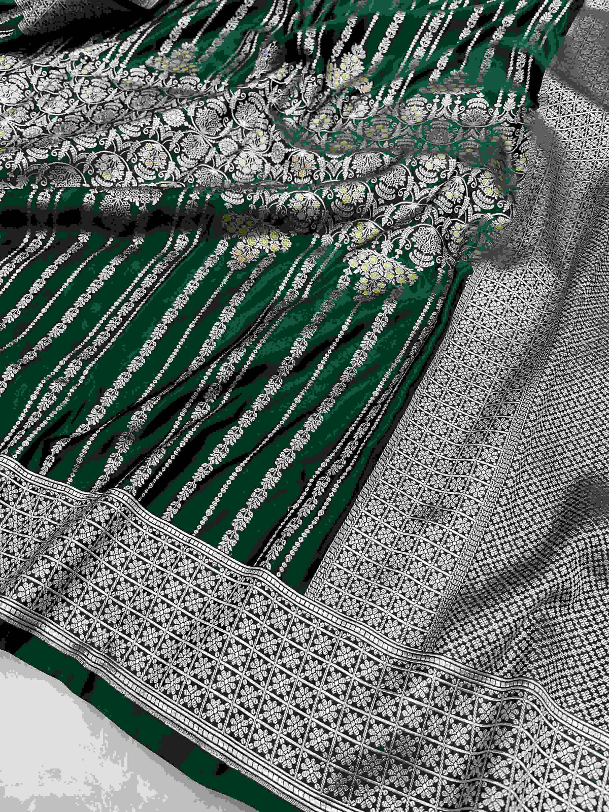Bottle green Banarasi mashru soft silk saree featuring all-over golden zari floral jangla weaving, delicate meenakari highlights, and intricate zari borders.
