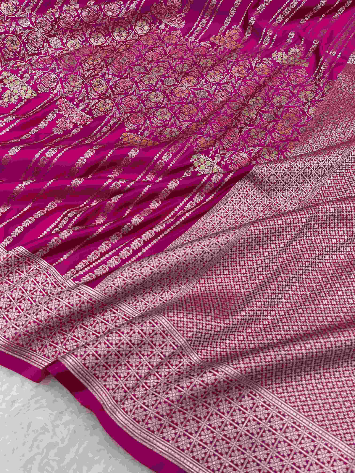 Hot pink Banarasi mashru soft silk saree detailed with all-over golden zari floral jangla weaving, meenakari highlights, and intricate zari borders.