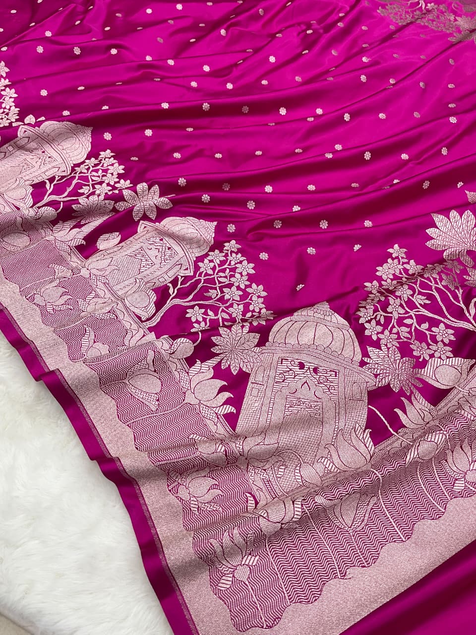 Rani Pink Banarasi Mashru soft silk saree richly patterned with intricate silver zari work, including floral motifs and a detailed border.