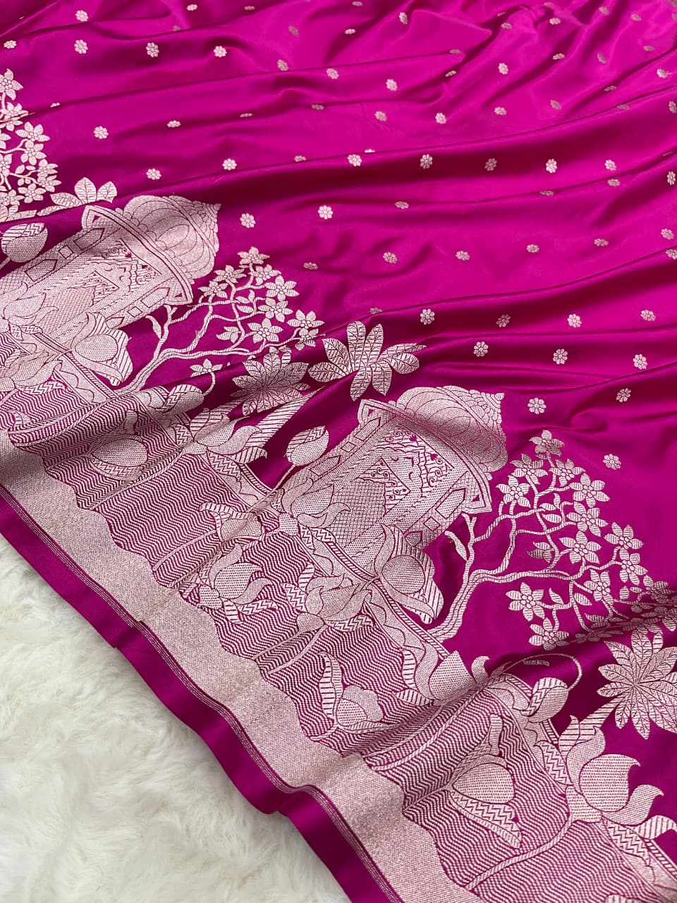 Rani Pink Banarasi Mashru soft silk saree richly patterned with intricate silver zari work, including floral motifs and a detailed border.
