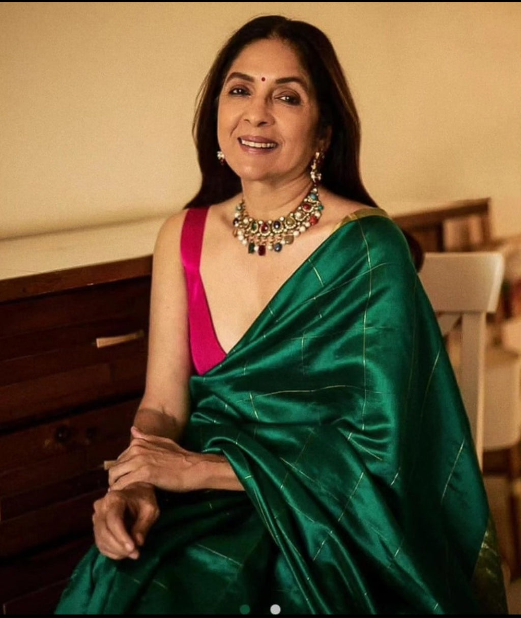 Elegant model wearing a bottle green Chanderi handloom pattu silk saree featuring all over zari checks in the body and traditional rich zari weaving.