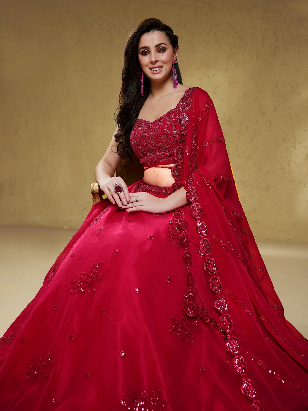 Model wearing a stunning red designer lehenga choli featuring intricate embroidery and a matching sheer dupatta