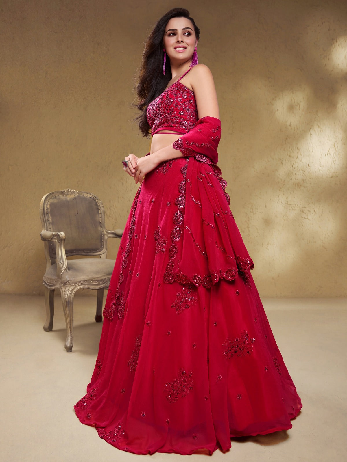Model wearing a stunning red designer lehenga choli featuring intricate embroidery and a matching sheer dupatta