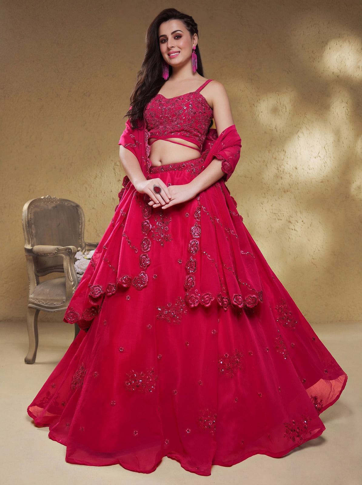 Model wearing a stunning red designer lehenga choli featuring intricate embroidery and a matching sheer dupatta