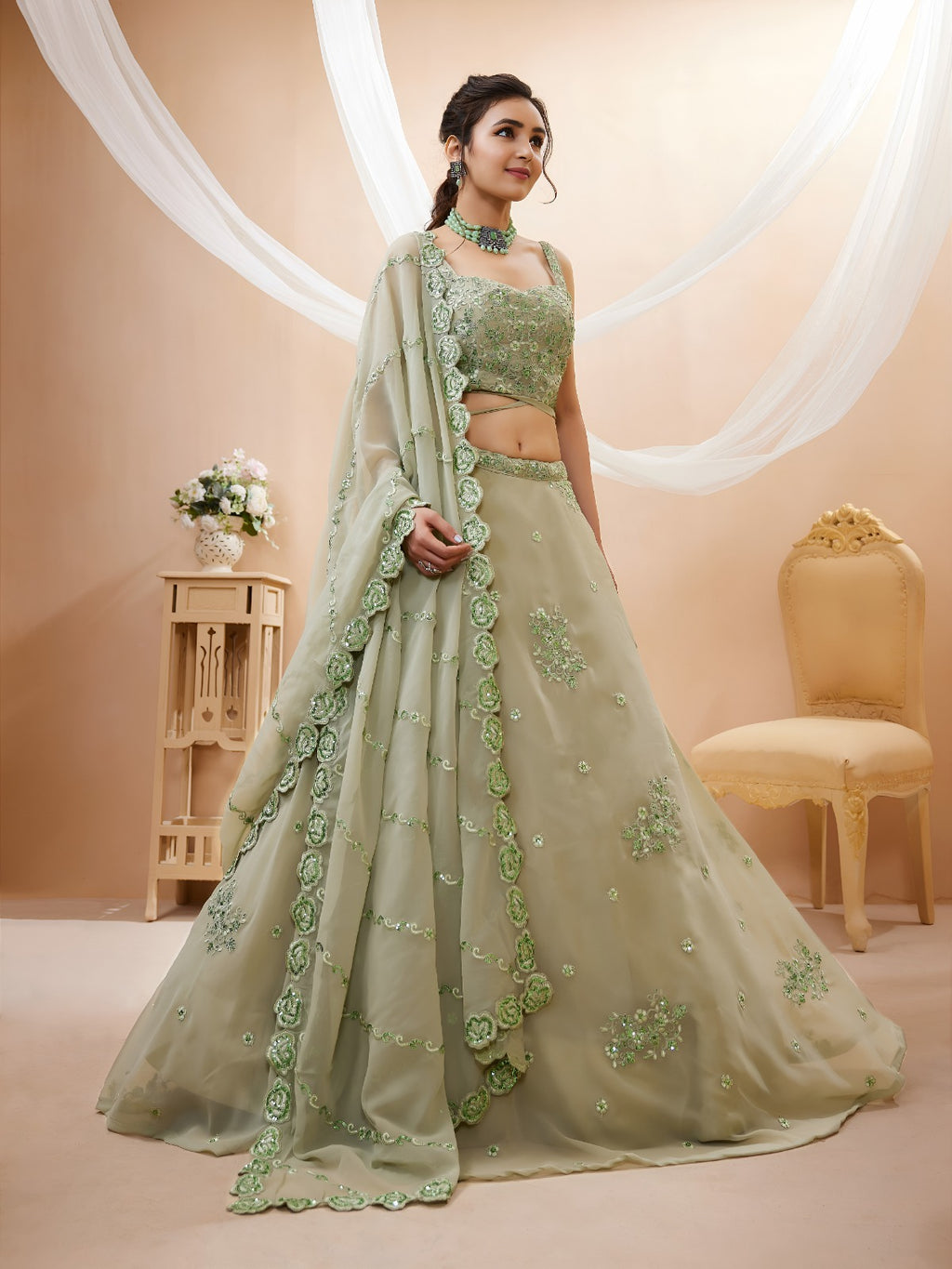 Model wearing a stunning pista green designer lehenga choli featuring intricate embroidery and a matching sheer dupatta