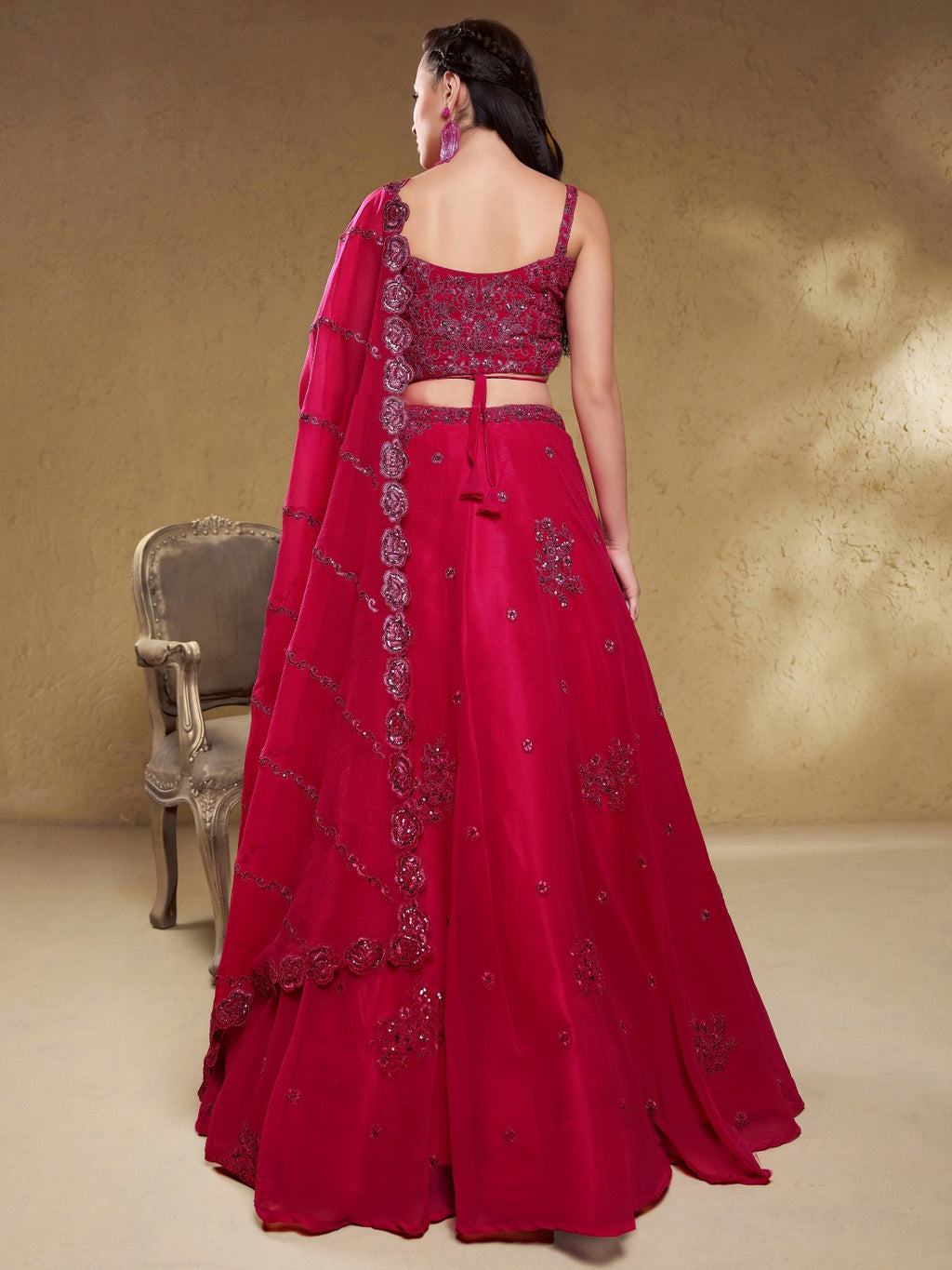 Model wearing a stunning red designer lehenga choli featuring intricate embroidery and a matching sheer dupatta