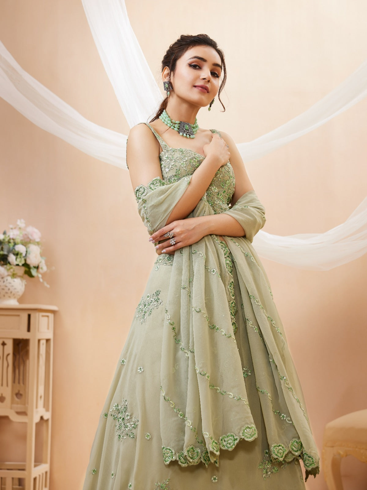Model wearing a stunning pista green designer lehenga choli featuring intricate embroidery and a matching sheer dupatta
