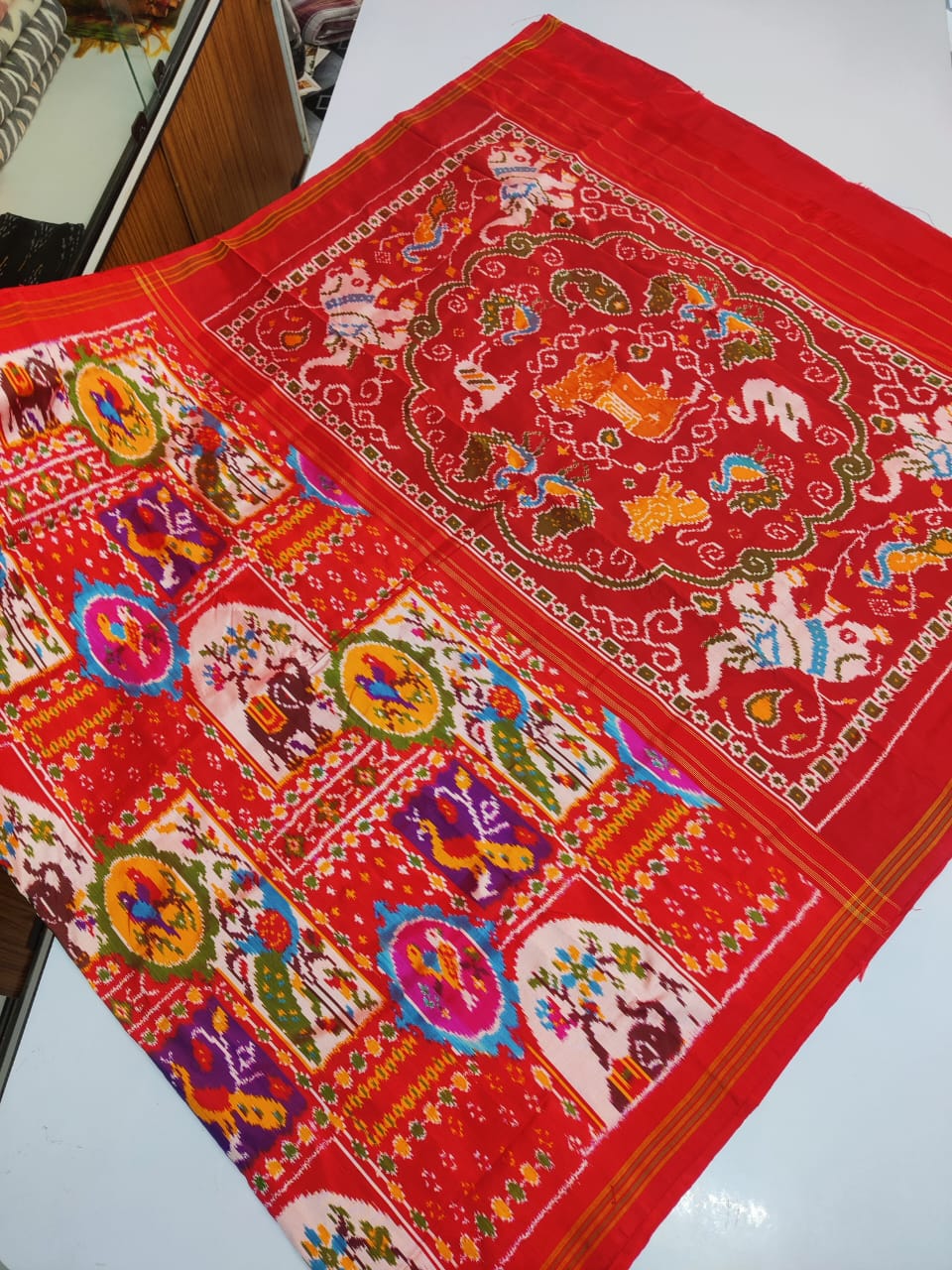 Red Pochampally Handloom Ikat Madthasu Patola Silk Saree featuring traditional double warp Ikat motifs, figurative panels, and a rich red pallu.