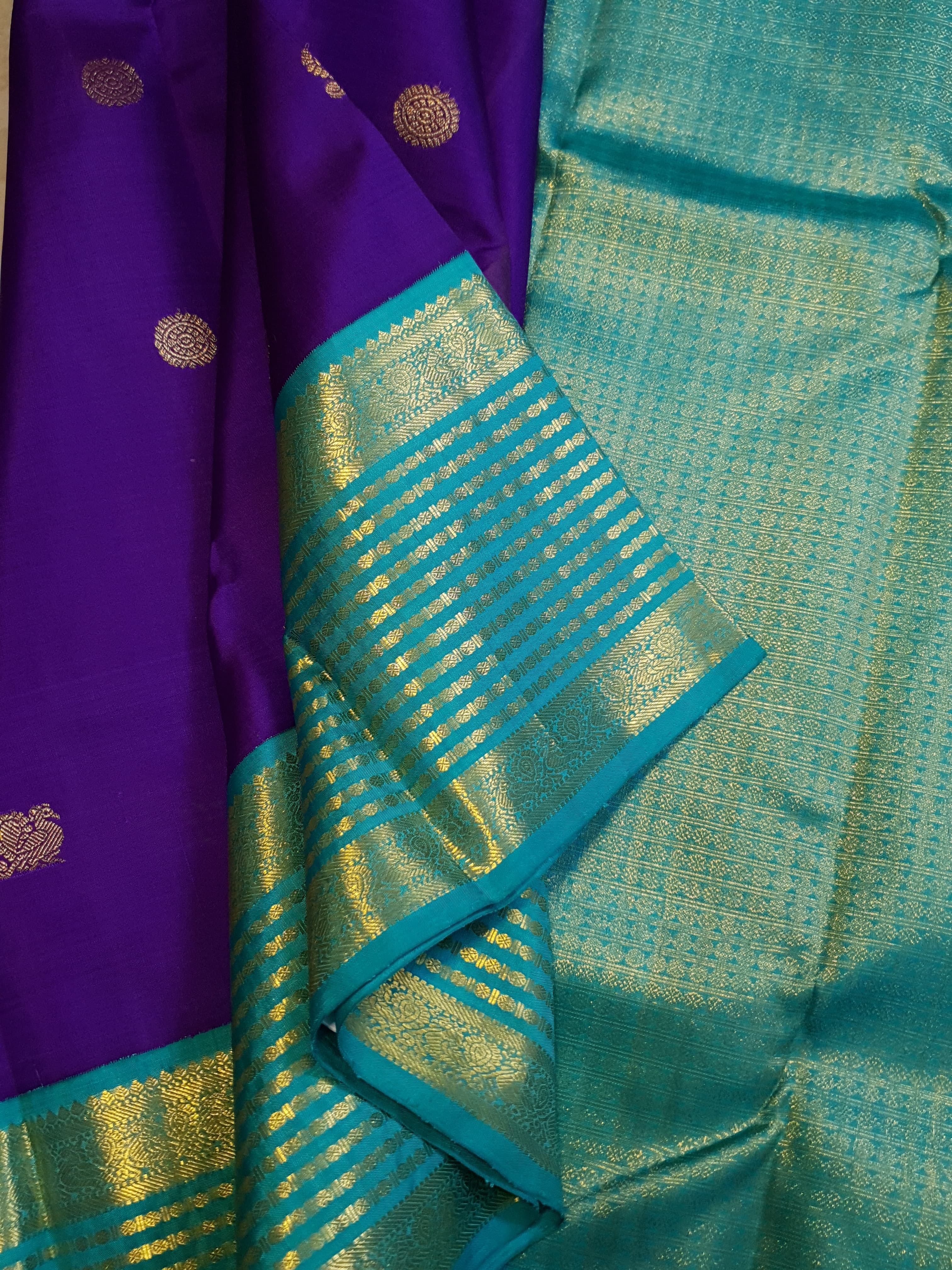 Purple Kanchipuram handloom 2G gold Korvai pattu silk saree showcasing a contrasting teal blue border with gold zari stripes.