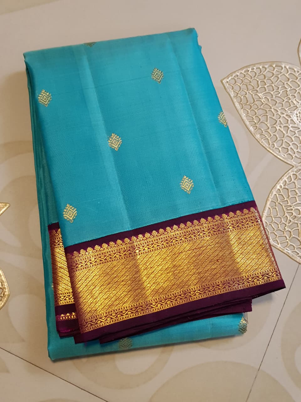 Vibrant turquoise blue Kanchipuram handloom silk saree with a contrasting deep purple korvai border and intricate gold zari work.