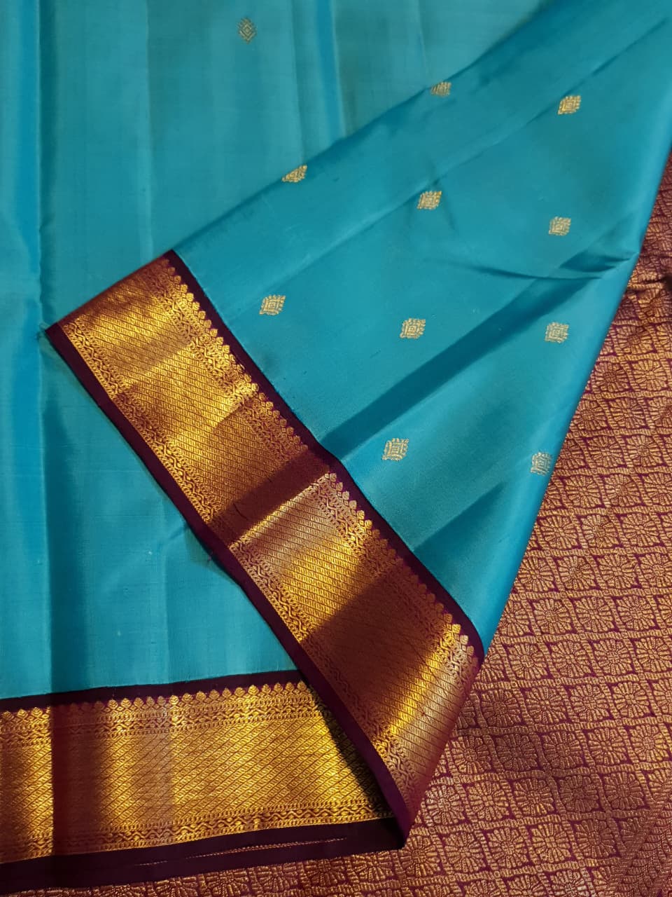 Vibrant turquoise blue Kanchipuram handloom silk saree with a contrasting deep purple korvai border and intricate gold zari work.