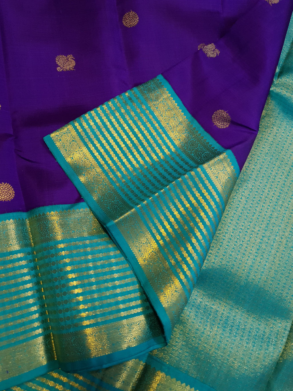 Purple Kanchipuram handloom 2G gold Korvai pattu silk saree showcasing a contrasting teal blue border with gold zari stripes.