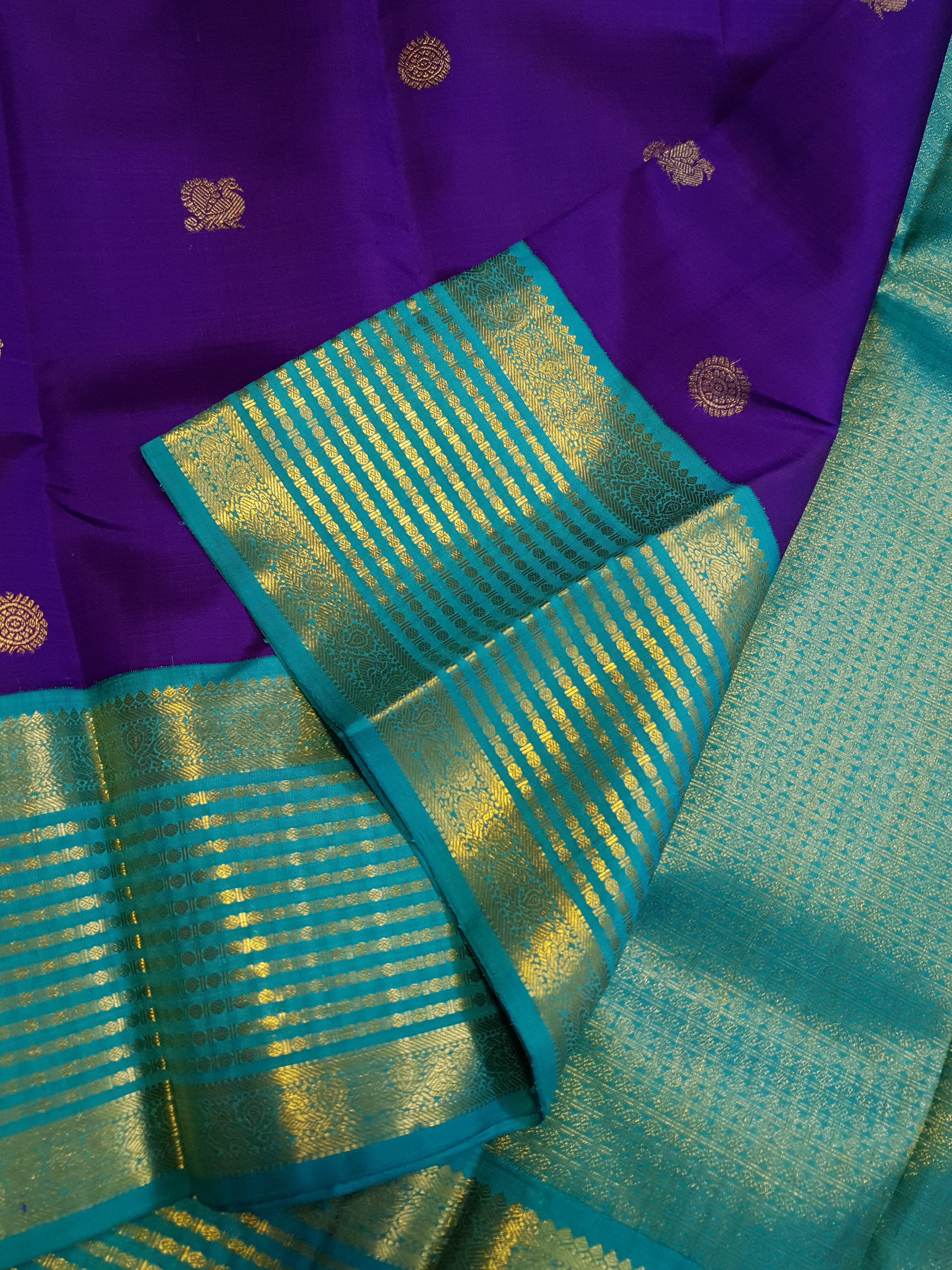 Purple Kanchipuram handloom 2G gold Korvai pattu silk saree showcasing a contrasting teal blue border with gold zari stripes.