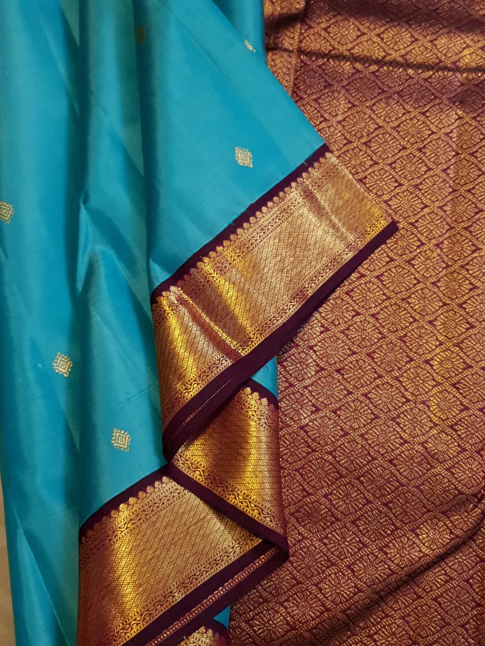 Vibrant turquoise blue Kanchipuram handloom silk saree with a contrasting deep purple korvai border and intricate gold zari work.
