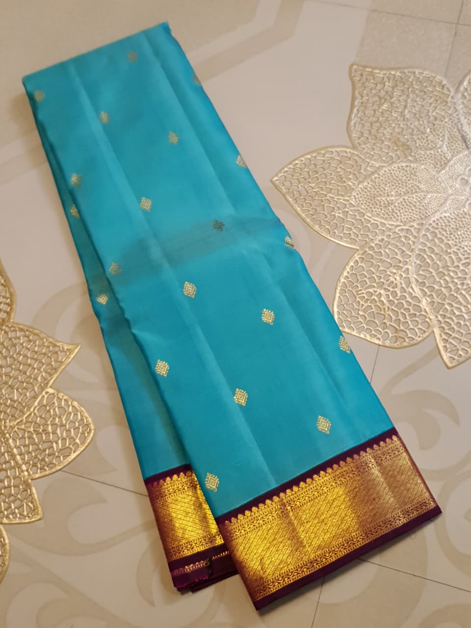 Vibrant turquoise blue Kanchipuram handloom silk saree with a contrasting deep purple korvai border and intricate gold zari work.