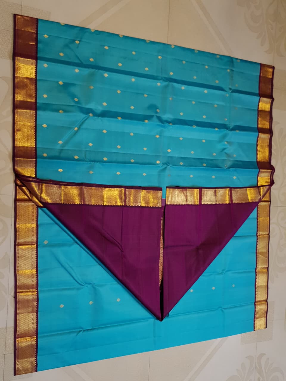 Vibrant turquoise blue Kanchipuram handloom silk saree with a contrasting deep purple korvai border and intricate gold zari work.