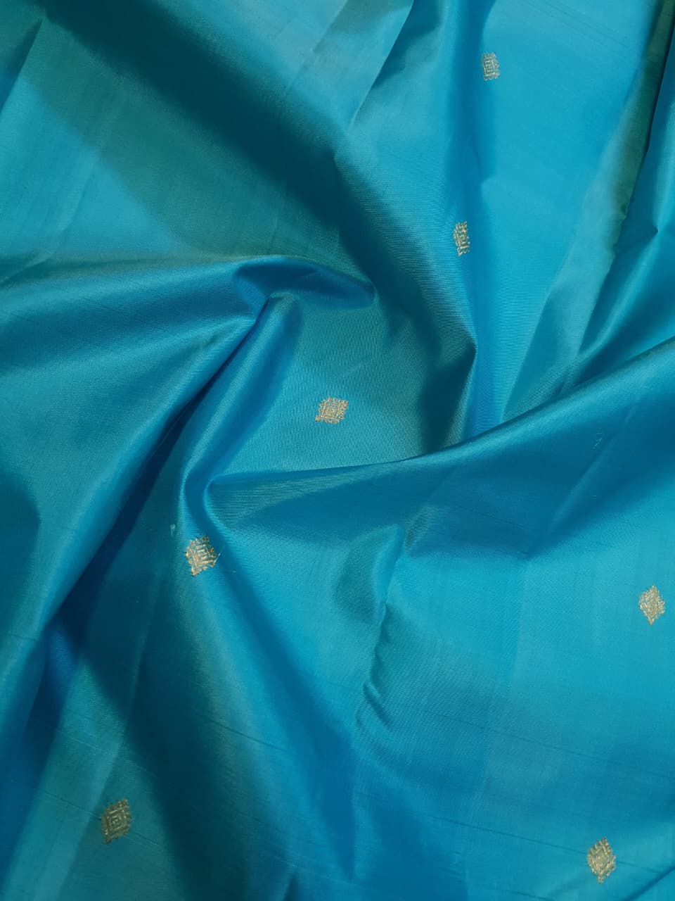 Vibrant turquoise blue Kanchipuram handloom silk saree with a contrasting deep purple korvai border and intricate gold zari work.