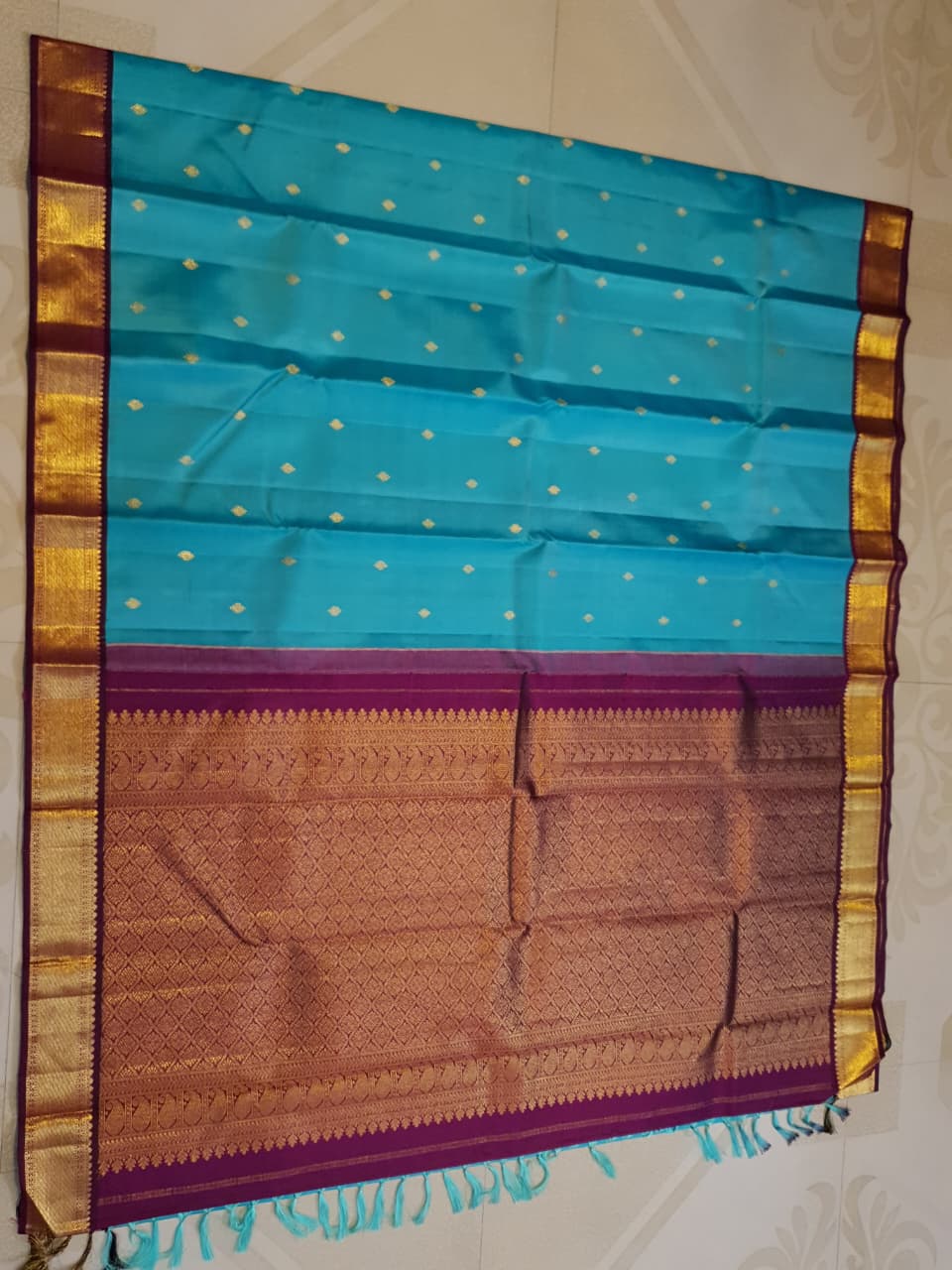 Vibrant turquoise blue Kanchipuram handloom silk saree with a contrasting deep purple korvai border and intricate gold zari work.