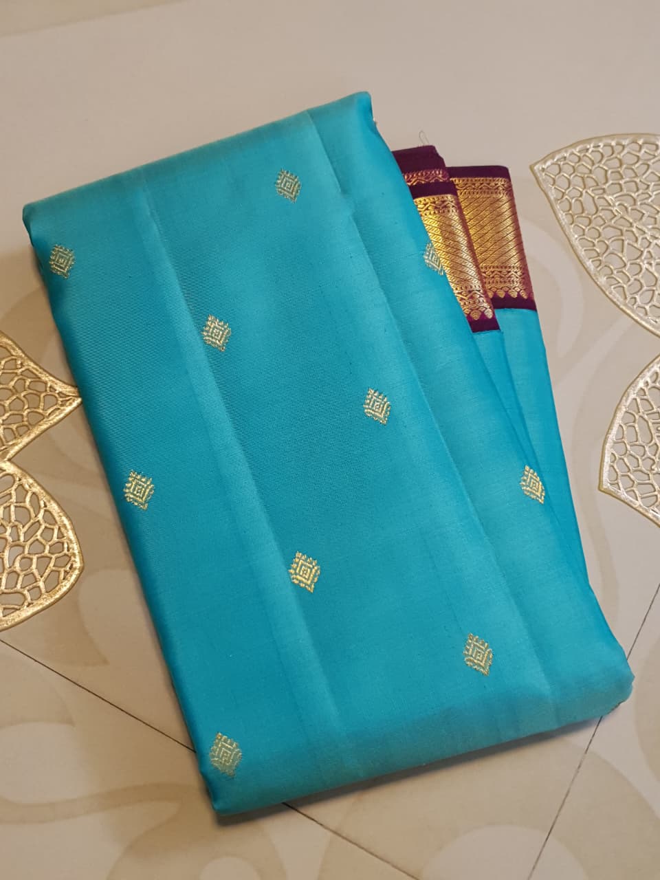 Vibrant turquoise blue Kanchipuram handloom silk saree with a contrasting deep purple korvai border and intricate gold zari work.