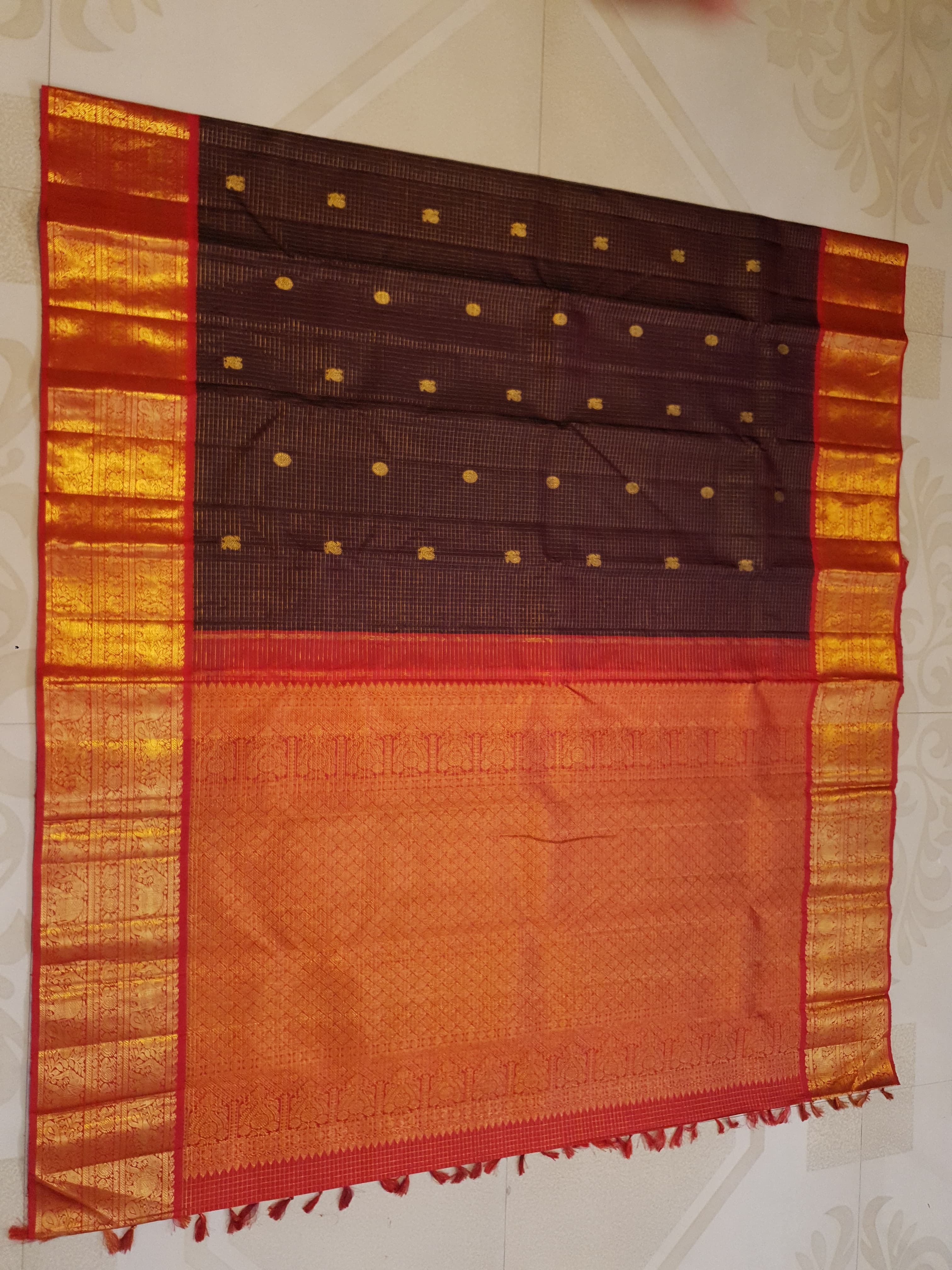 Dark plum Kanchipuram silk saree featuring a gold Muthukattam check pattern, ornate zari buttas, and a vibrant contrast border and pallu.