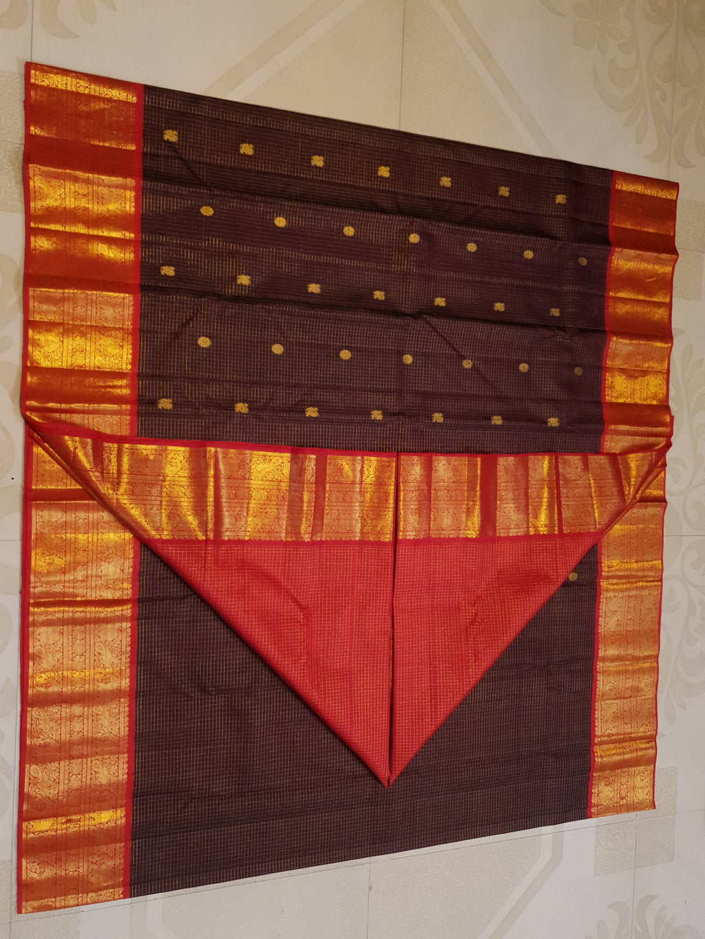 Dark plum Kanchipuram silk saree featuring a gold Muthukattam check pattern, ornate zari buttas, and a vibrant contrast border and pallu.