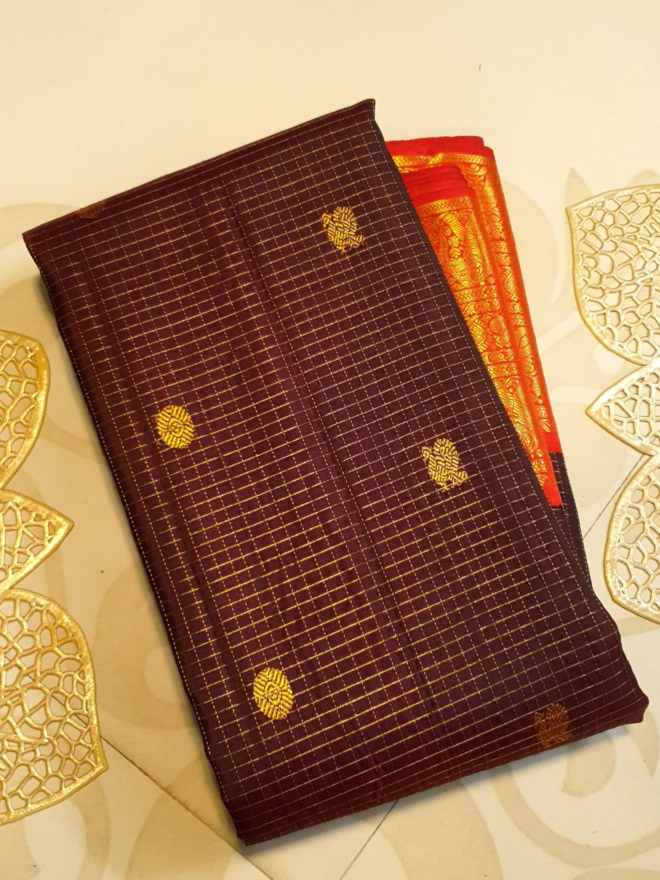 Dark plum Kanchipuram silk saree featuring a gold Muthukattam check pattern, ornate zari buttas, and a vibrant contrast border and pallu.