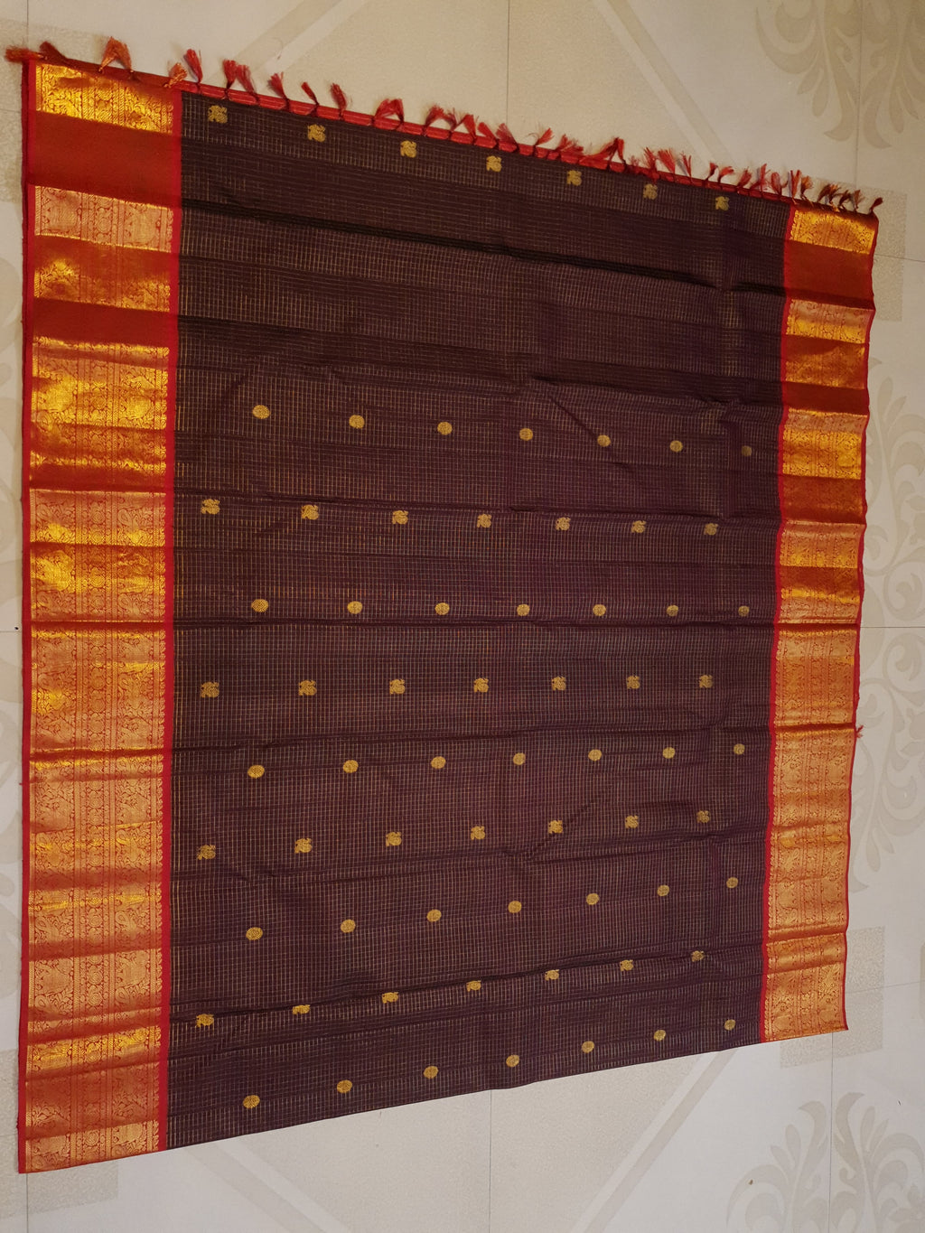 Dark plum Kanchipuram silk saree featuring a gold Muthukattam check pattern, ornate zari buttas, and a vibrant contrast border and pallu.