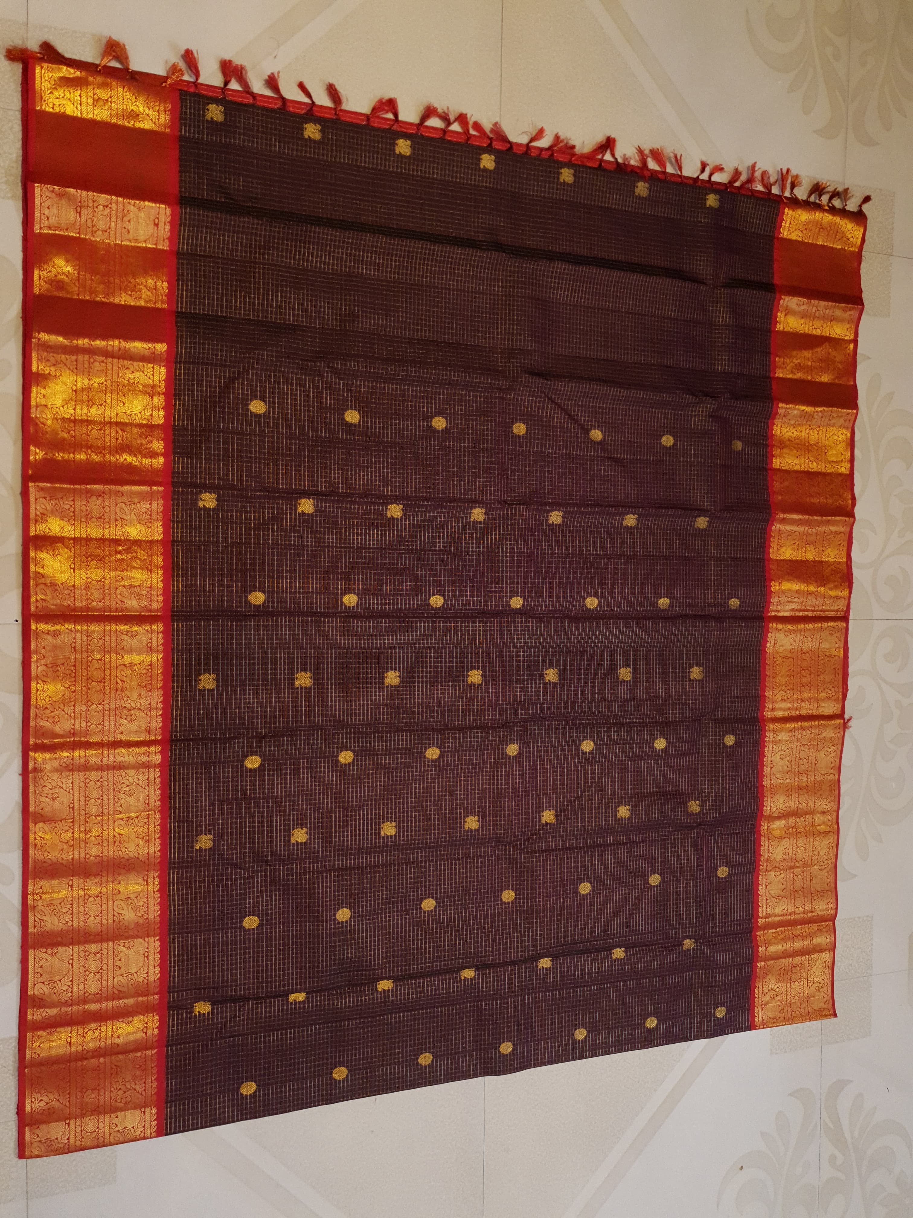 Dark plum Kanchipuram silk saree featuring a gold Muthukattam check pattern, ornate zari buttas, and a vibrant contrast border and pallu.