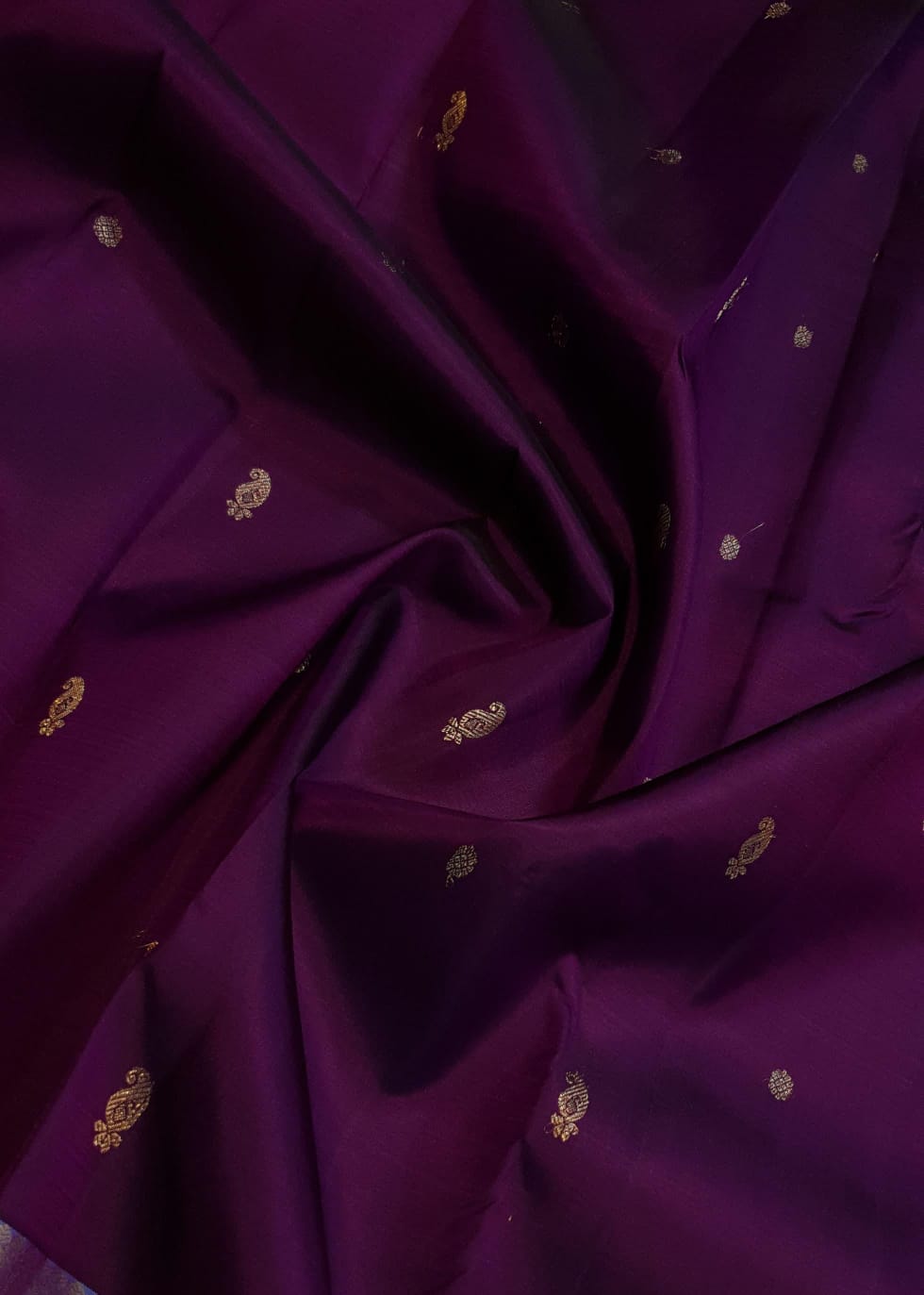 Dark plum Kanchipuram silk saree featuring a gold zari buttas, and a vibrant contrast border and pallu.